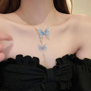 Macro view of a gold-tone necklace featuring blue tulle butterflies and tassel details