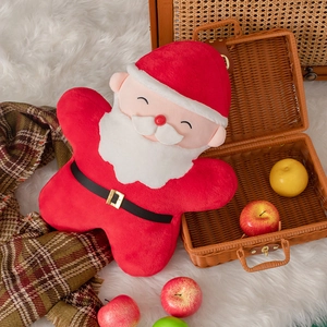 Detail of Santa Claus plush pillow on white blanket with festive holiday decorations