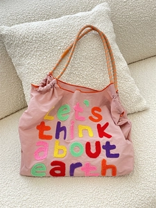 Detail of pink canvas tote featuring colorful 'earth' embroidery and rope handles