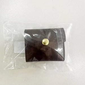 Detail of a dark brown mini leather jewelry pouch with gold snap button in packaging