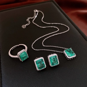 Detailed view of silver zircon jewelry set with square emerald stones in a luxury gift box