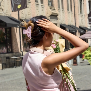 Pince à cheveux rose en acétate en forme de cœur portée par un mannequin en extérieur
