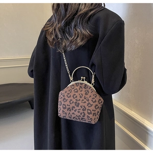 Detail of leopard print shell bag with golden pearl handle and chain strap on shoulder