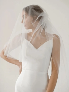 Detail of elegant two-layer bridal veil with V-neck satin wedding gown and long tulle train
