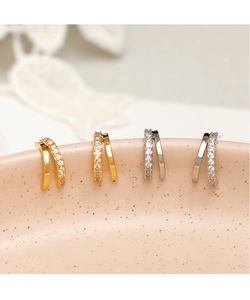 Macro detail of gold and silver double-row crisscross stud earrings with zircon inlay