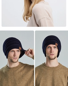 Detail of navy blue ribbed knit beanie featuring a brown leather logo patch on the side