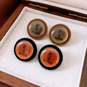 Macro shot of vintage round acrylic button earrings in a brown wooden jewelry box