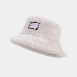 Détail d'un bob en peluche crème avec un écusson violet brodé 'MAKE IT HAPPEN' chic
