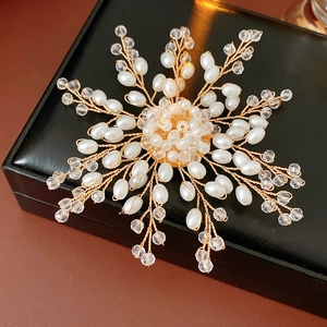 Detailed macro view of handmade snowflake brooch with white pearls and gold wire craft