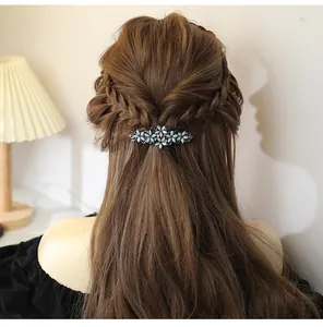 Detail of floral hair clip with blue petals and rhinestones on braided hair