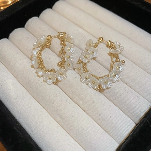 Boucles d'oreilles fleurs en acrylique et anneaux dorés dans un écrin à bijoux en velours