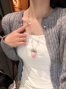 Detail of pink strawberry pendant with pearls and silver chain worn in casual setting