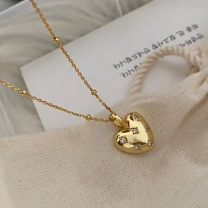 Macro shot of gold heart necklace with sparkling diamonds on a vintage beaded chain