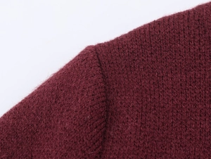 Close-up of shoulder seam detail on burgundy knit dress with faux fur stitching