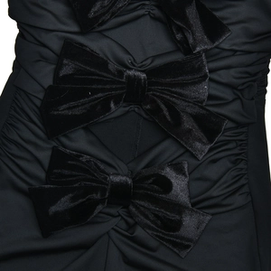 Detailed view of black velvet bows and ruched texture on a slim-fit strapless bodysuit