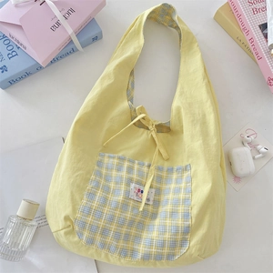 Macro detail of yellow pleated canvas hobo bag with blue checkered pocket and soft texture