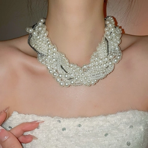 Close-up of layered pearl statement necklace with metal chains on female neck