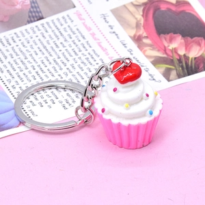 Close-up of a cute cupcake keychain with pink base and white cream on a pink surface
