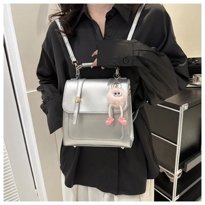 Détail d'un sac à dos argenté métallisé avec peluche rose porté par le mannequin