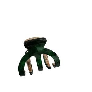 Deep green marble texture acetate hair claw clip with golden metal teeth on white background