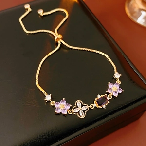 Close-up of adjustable gold flower bracelet with purple and white zircon on leather box