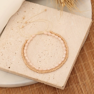 Detail of handmade beaded bracelet set with adjustable drawstring on textured stone surface