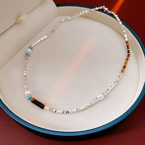 Detail of beaded necklace with silver chips, white pearls and tiger eye accents