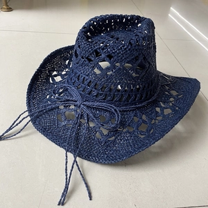 Detail of navy blue hand-woven straw cowboy hat with cutout patterns and decorative bow