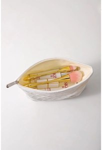 Dettaglio trousse bianca testurizzata con pennelli e cosmetici all'interno