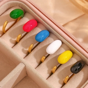 Close-up of adjustable gold rings with colorful teardrop enamel inserts in jewelry box