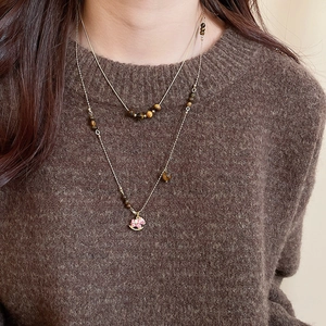 Détail d'un collier à deux rangs avec perles oeil de tigre et pendentif cheval en émail