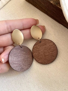 Detail of vintage geometric earrings with golden oval metal and dark round wood discs