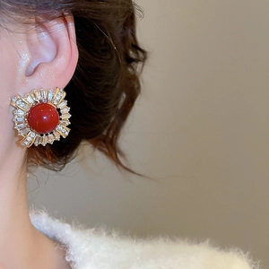 Detailed close-up of vintage gold stud earrings with a red gemstone and zircon halo
