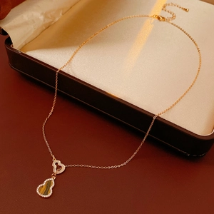 Macro detail of gold heart and zircon gourd pendant necklace in a velvet jewelry box
