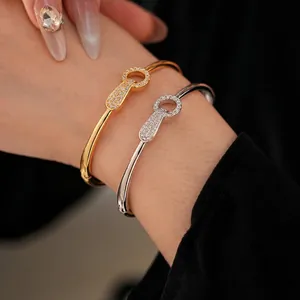 Gold and silver plated bangles with zircon lock pendants worn on a model's wrist