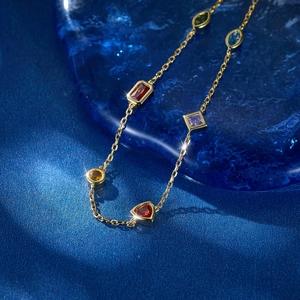 Macro shot of colorful geometric gemstones on a gold S925 silver bracelet with blue background