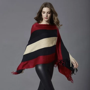 Close-up of color-block striped knit poncho featuring elegant red and black fringe detail