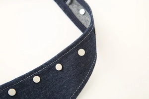 Close-up of dark blue denim halter strap with silver metal studs and white topstitching