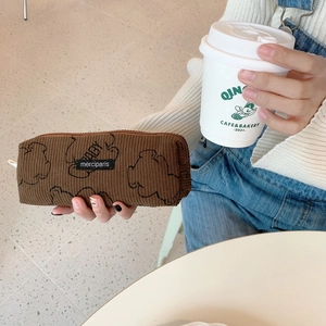 Close-up of hand holding a brown corduroy bear pencil case with a zipper closure