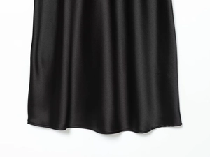 Detailed macro view of the glossy black satin hemline with fine sewing and drape