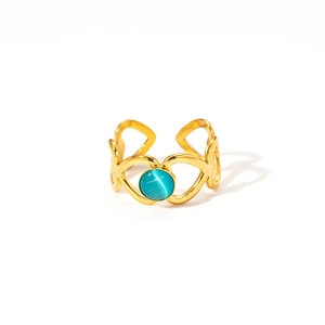 Détail d'une bague ouverte dorée 18k avec motifs cœurs ajourés et pierre verte