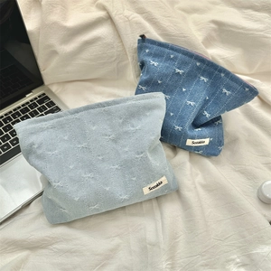 Detail of denim cosmetic bags with heart and bow embroidery in light and dark blue