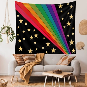 Rainbow stripe wall tapestry with gold stars displayed over a cozy living room sofa