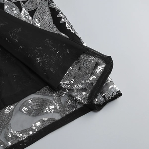 Vue détaillée du tissu en maille noire avec broderie de paillettes argentées
