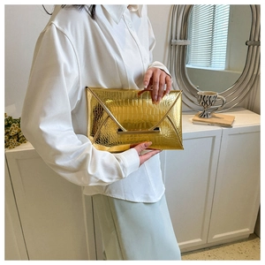 Detailed macro view of the gold envelope clutch bag featuring metallic crocodile texture