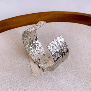Vista de primer plano del brazalete plateado con textura martillada y calados