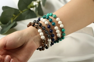 Detail shot of multiple natural lava and imperial stone elastic bead bracelets on wrist