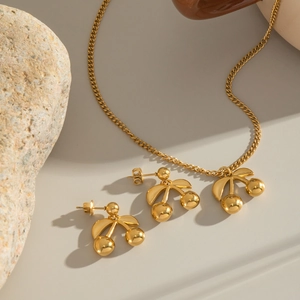 Detailed view of 18K gold cherry pendant necklace and matching stud earrings set
