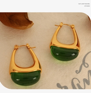 Detail of vintage teardrop earrings with green gemstones and gold polished U-shaped frame