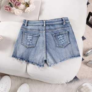 Close-up of light blue high waist denim shorts featuring distressed holes and frayed hem